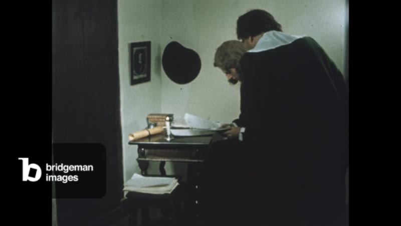 Image of 1960s: Man writing a letter, another man brings more papers.