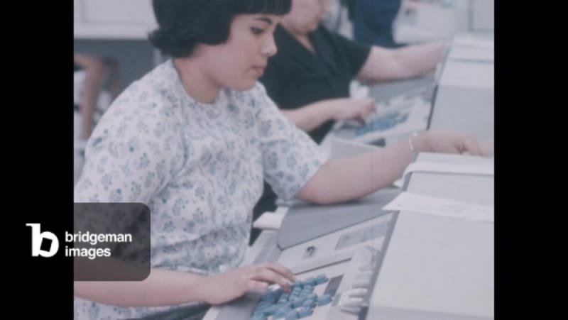 Image of 1960s: Line of workers sit at keypunch data entry machines,